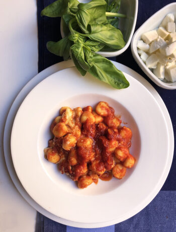 gnocchi alla sorrentina served on a white dish with basil and mozzarella