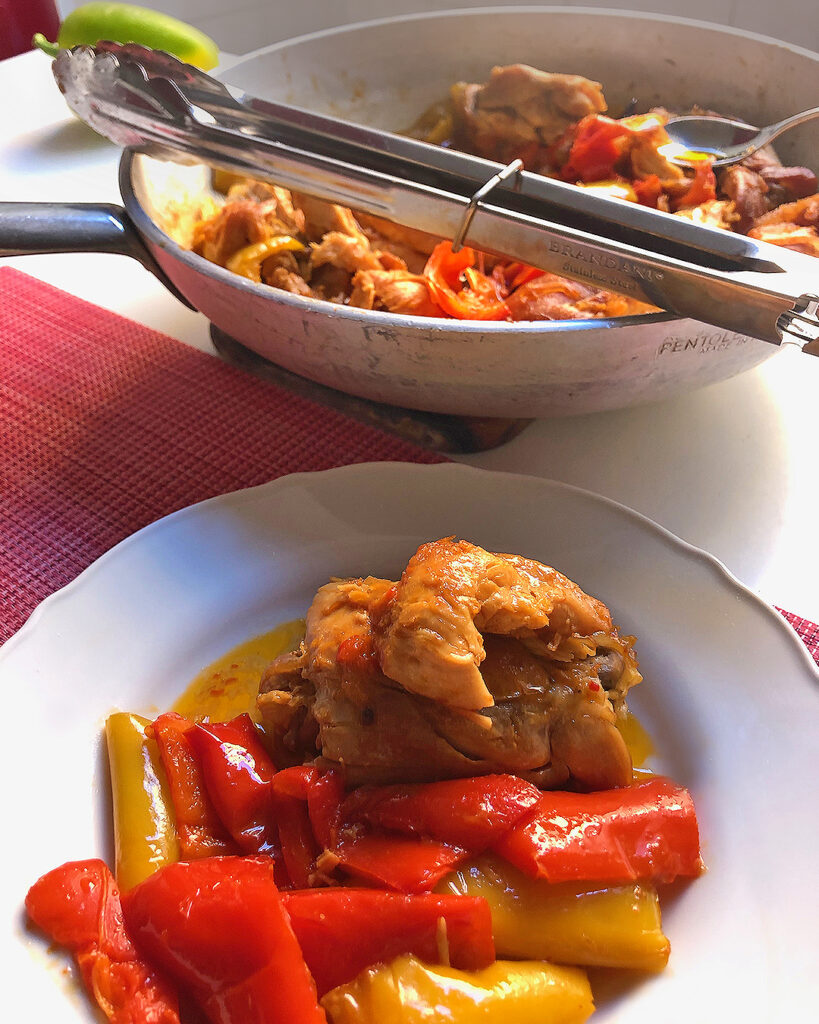 chicken with bell pepper on a with dish, with on the back the pan where it was cooked